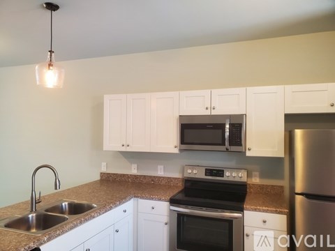 A kitchen with white cabinets and a stainless steel refrigerator.
