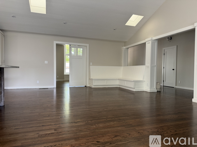 A spacious room with wooden floors and white walls.