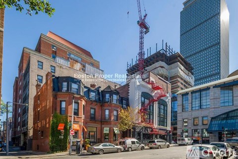 A city street with a building under construction and a crane in the background.