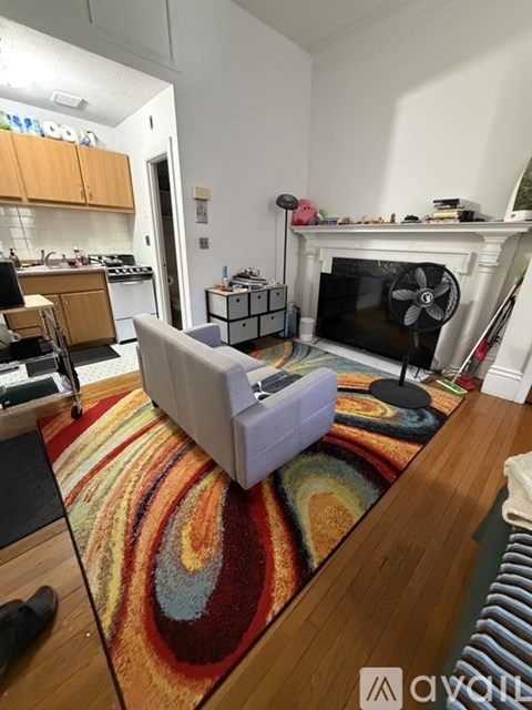 A living room with a white couch and a colorful rug.