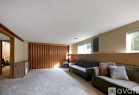 A living room with a grey sofa and a wooden wall.