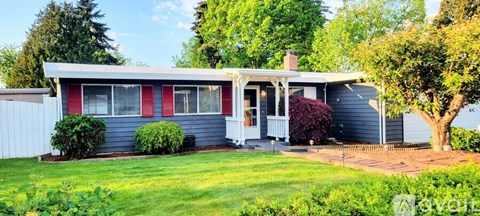 A house with a red stripe on the wall and a white fence.