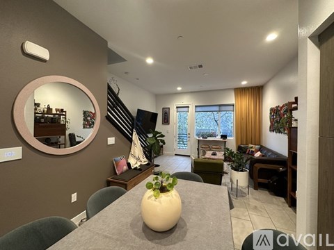 A living room with a grey table and a round mirror on the wall.