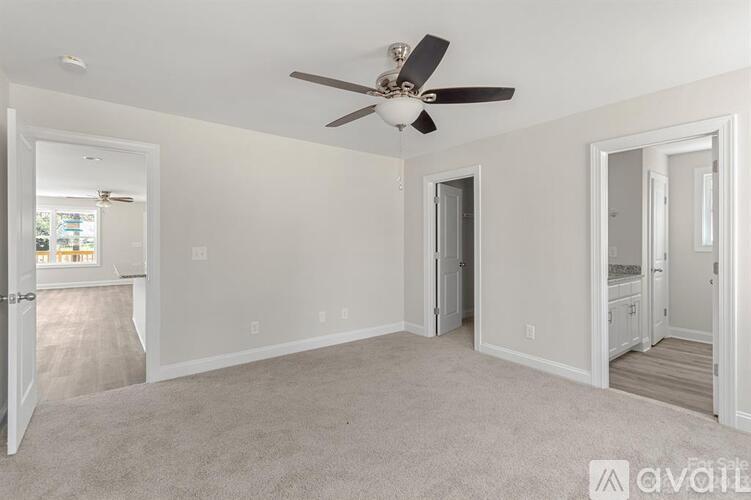 A spacious room with a ceiling fan and carpeted floor.