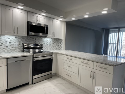 A modern kitchen with white cabinets and stainless steel appliances.