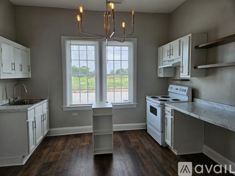 A kitchen with white cabinets and a window overlooking a field.