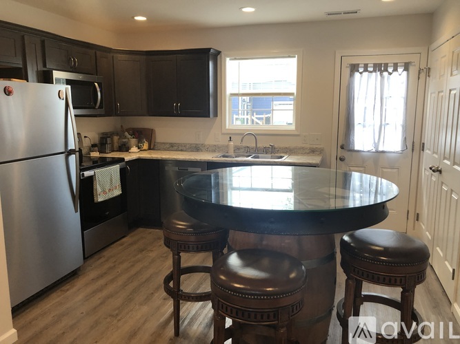 A kitchen with a black countertop and a stainless steel refrigerator.