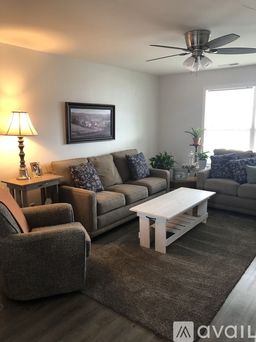 A living room with a grey couch, a white coffee table, and a ceiling fan.
