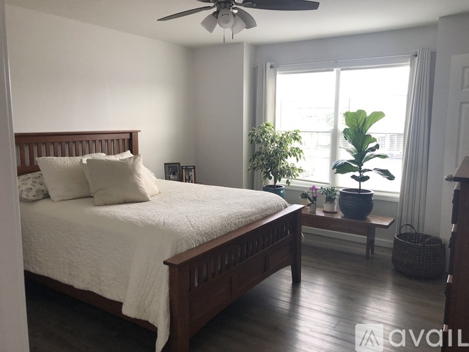 A bedroom with a bed, a window, and a potted plant.