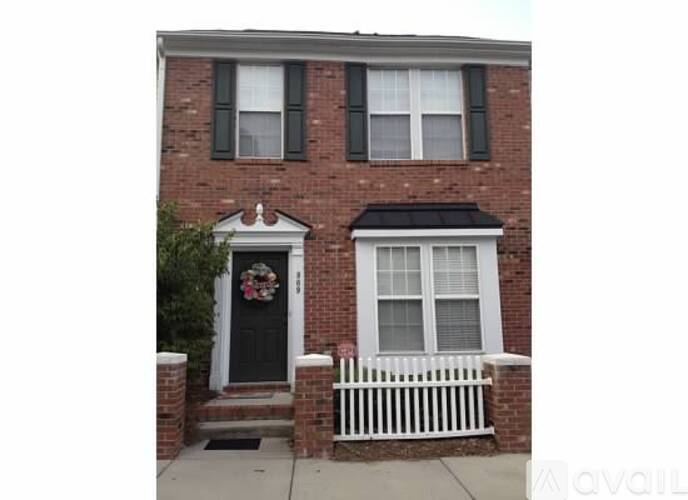 A brick house with a black door and a white fence.