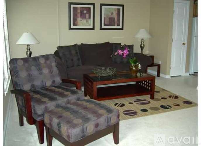 A living room with a grey couch, a matching chair and a coffee table with a vase of flowers on it.