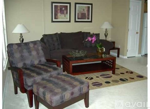 A living room with a grey couch, a matching chair and a coffee table with a vase of flowers on it.