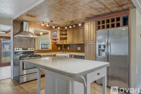 A kitchen with a stainless steel refrigerator and a granite countertop.