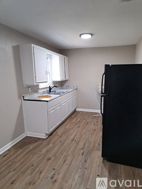 A kitchen with white cabinets and a black refrigerator.
