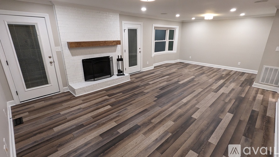 A room with wooden flooring and a fireplace.