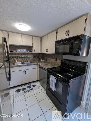 A kitchen with white cabinets and black appliances.