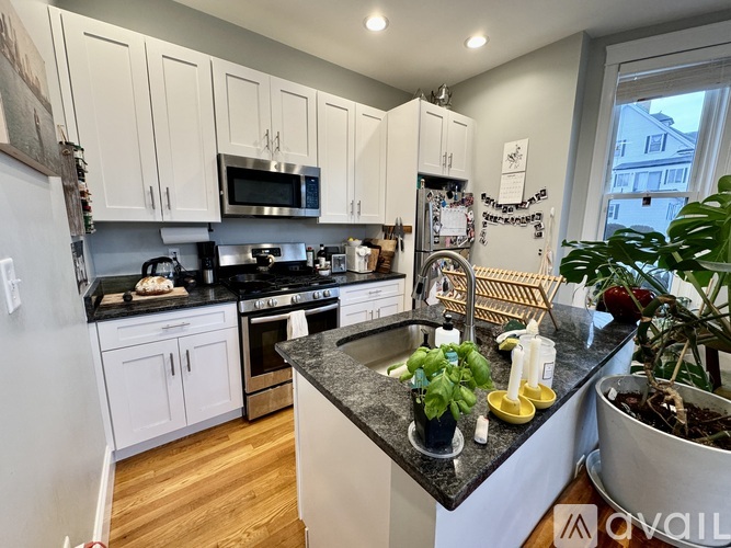 A kitchen with white cabinets and black countertops.