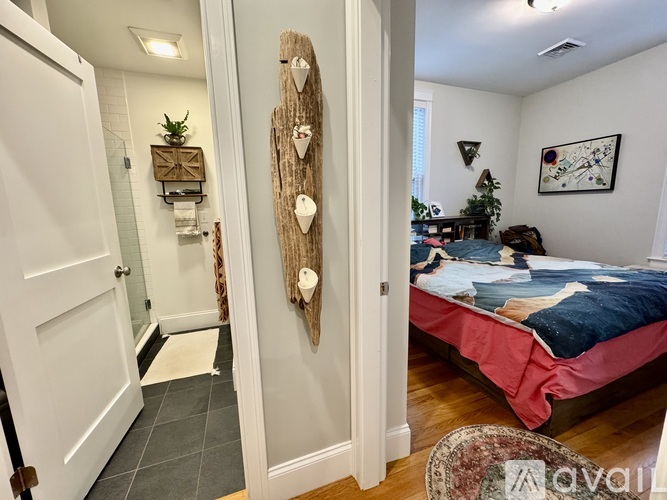 A bedroom with a bed, a wooden wall hanging, and a rug on the floor.