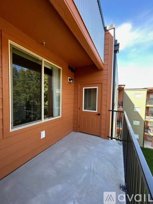 A balcony with a black railing and a brown door.