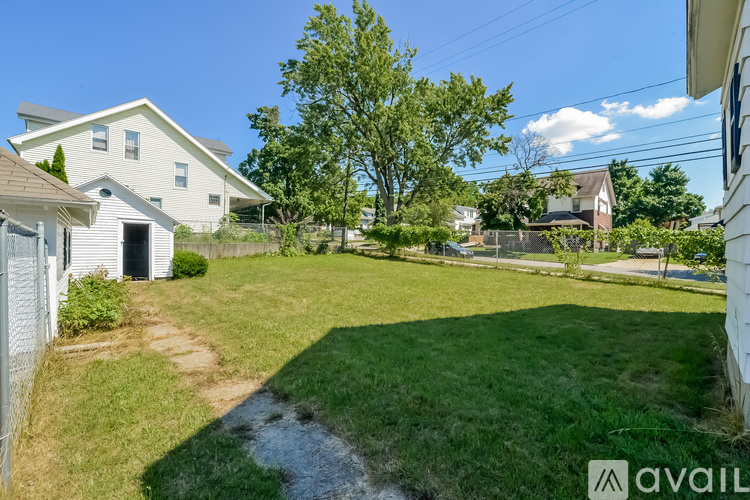 A backyard with a grassy area, a tree, and a small stream running through it.