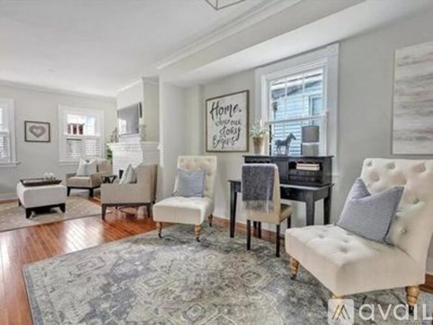 A living room with a white chair and a grey rug.