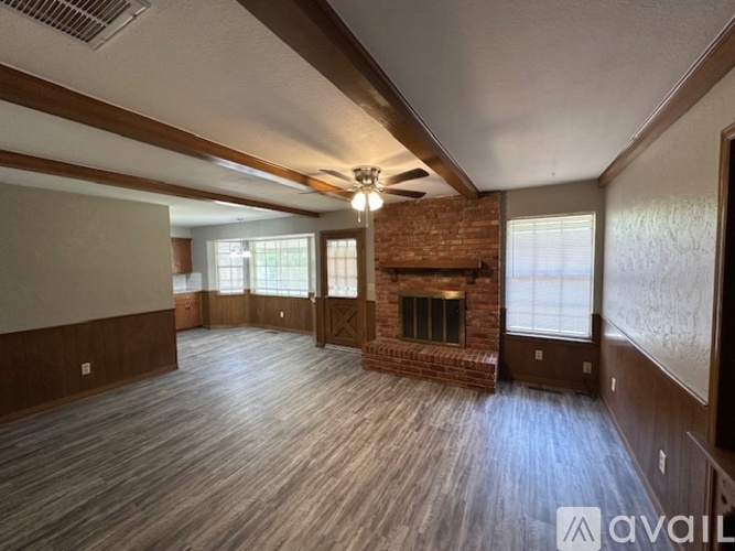 A spacious room with wood flooring and a brick fireplace.