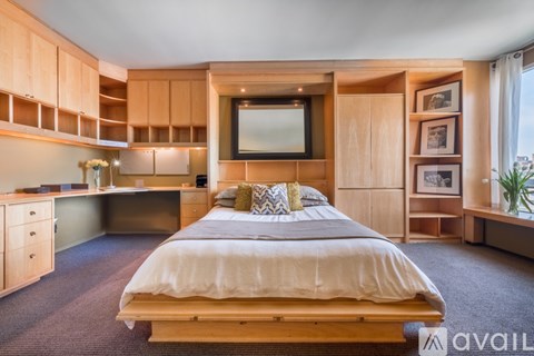 A bedroom with a bed, desk, and shelves.