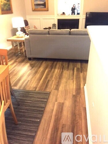 A living room with a grey couch and a wooden floor.