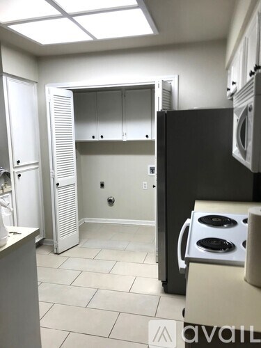 A kitchen with a black refrigerator and white cabinets.
