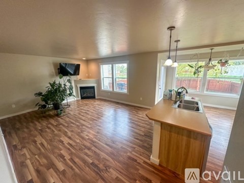 A living room with wood flooring and a television mounted on the wall.