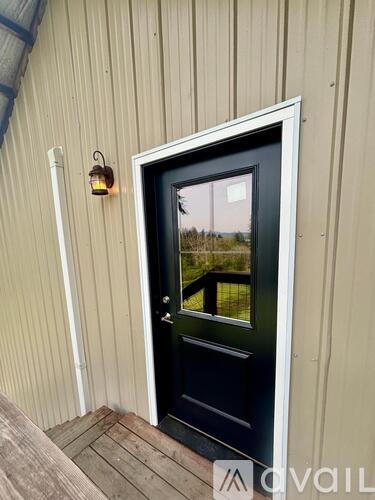 A black door with a glass window is set in a wooden frame.