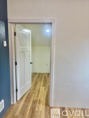 A hallway with a white door and wooden floor.