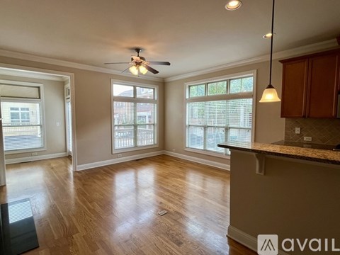 A spacious room with wooden floors and a ceiling fan.