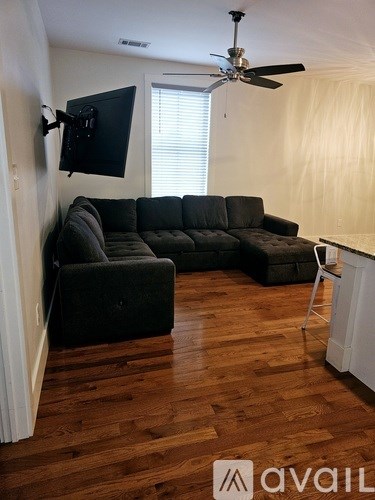 A living room with a black sofa and a television mounted on the wall.