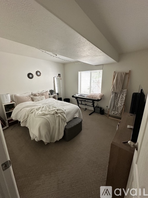 A bedroom with a bed, a chair, and a window.