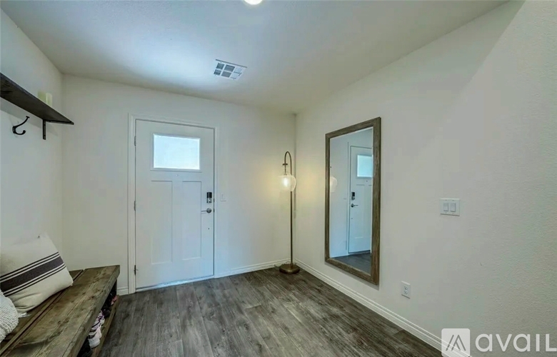 A room with a white door, a mirror, and a wooden bench.