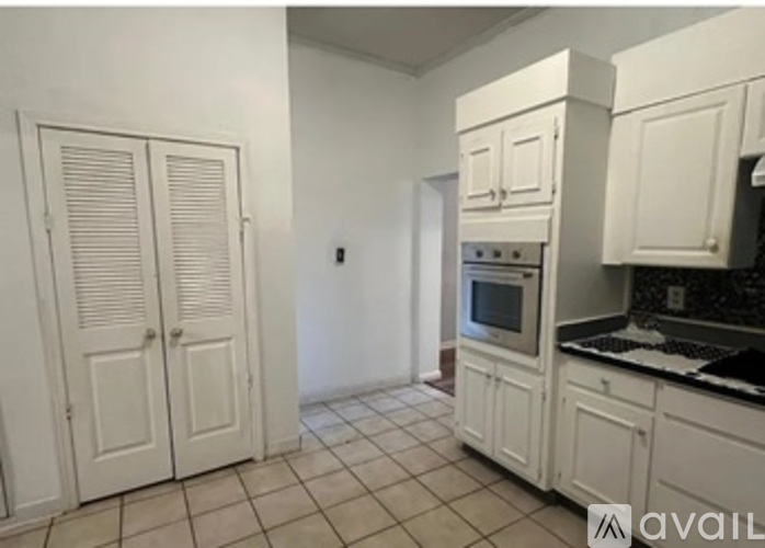 A kitchen with white cabinets and a tiled floor.