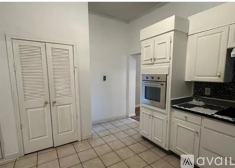 A kitchen with white cabinets and a tiled floor.