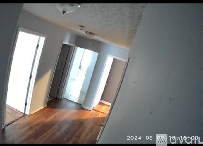 A room with wooden floors and white walls, with a window letting in natural light.