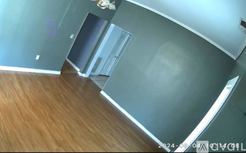 A room with a wooden floor and a grey wall.