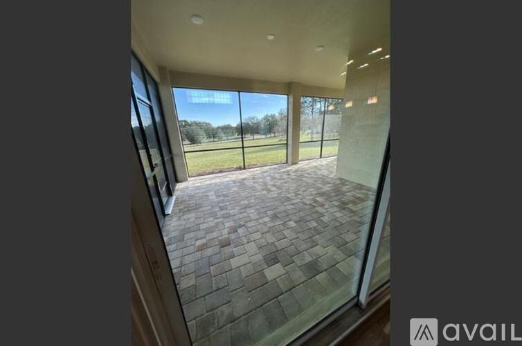 A balcony with a tiled floor and glass walls overlooking a grassy field.