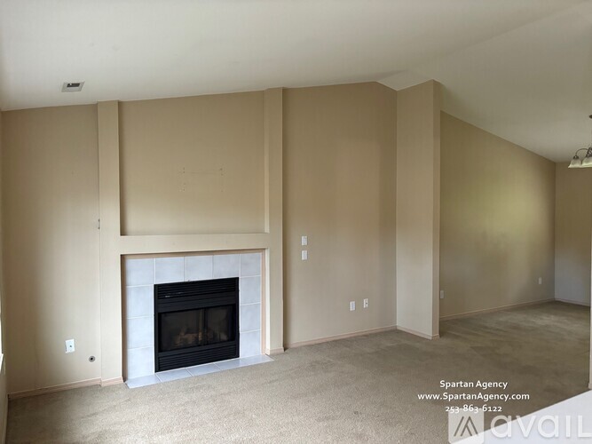 A living room with a fireplace and a Spartan Agency logo.