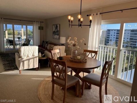 A living room with a dining table and chairs, a sofa, and a view of the city.