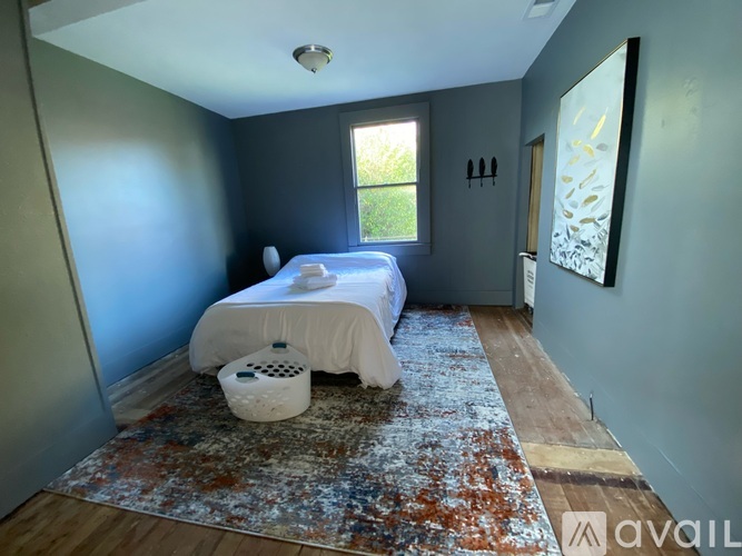 A bedroom with a bed, rug, and a window.