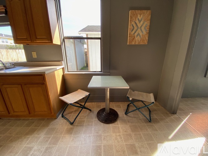 A kitchen with a table and two chairs.