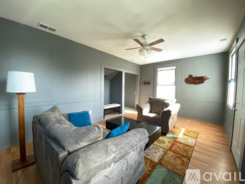 A living room with a grey couch and a wooden floor lamp.