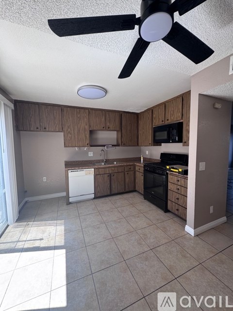A kitchen with a fan on the ceiling and a washing machine in the corner.