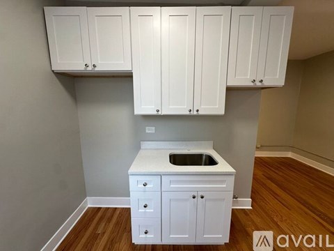A kitchen with white cabinets and a white island with a sink.