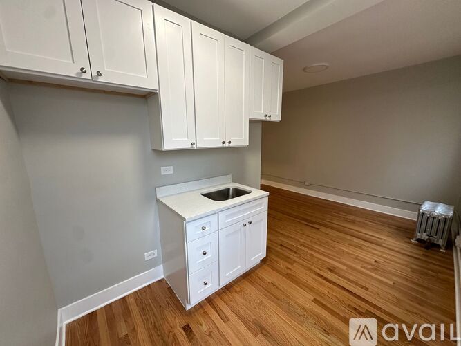 A kitchen with white cabinets and a wooden floor.