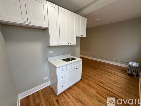 A kitchen with white cabinets and a wooden floor.